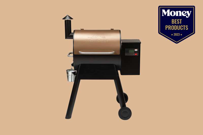 A pellet grill with a copper hood and black body on a sand-colored backdrop