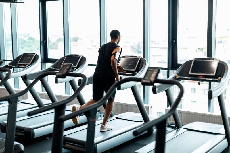 Cardio Training. Black Man Running On Treadmill Near Panoramic Window At Gym