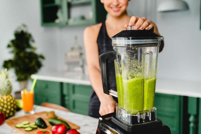 Close up photo of a girl making detox cocktail using blender in the kitchen