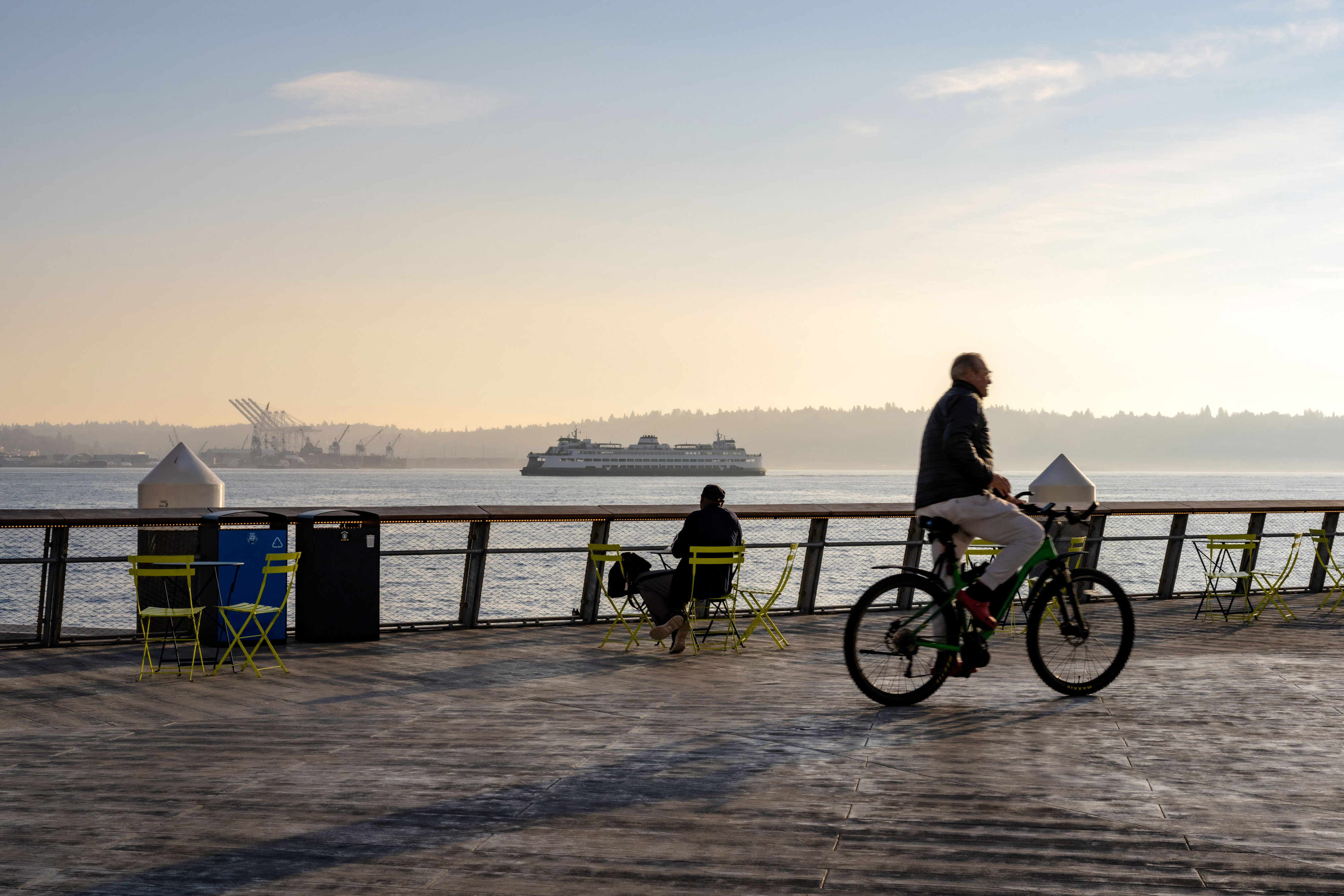 Man on a bike at pier, with a Ferry Boat in the background in Seattle