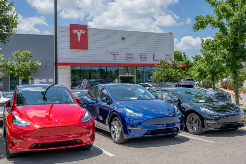 Tesla vehicles sit on the lot for sale at a Tesla car dealership