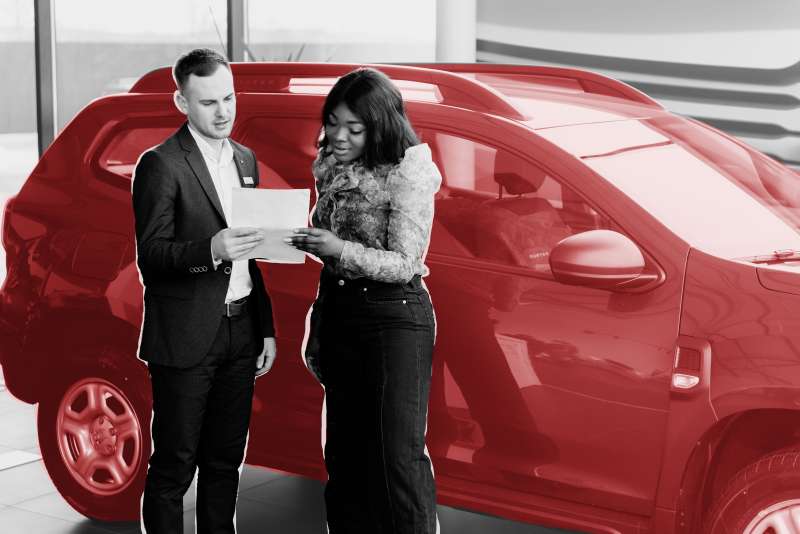 Woman and car salesman looking at a piece of paper while standing in-front of a new SUV