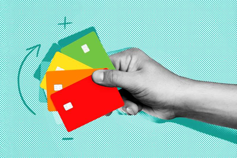 Hand holding multiple credit cards fanned out in a color sequence matching a credit wheel, red, orange, yellow and green