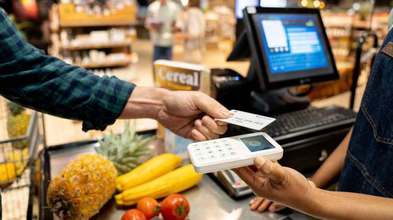 Person paying groceries using a debit card to build credit