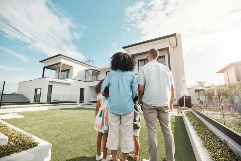 Family of four standing in-front of a beautiful house