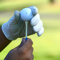 Hands holding golf ball on a golf tee
