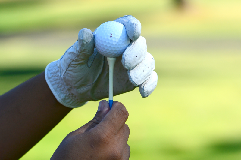 Hands holding golf ball on a golf tee