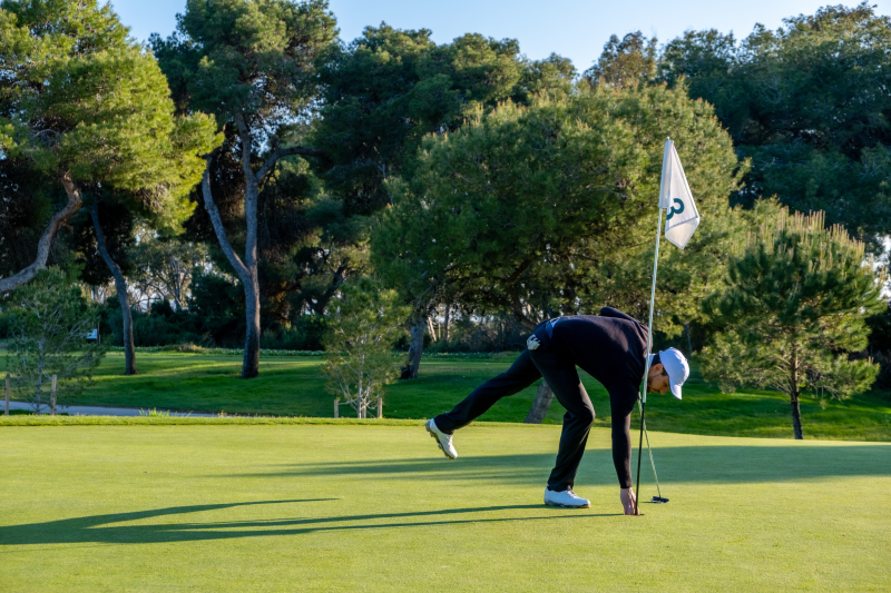 Golf player takes the ball out of the hole