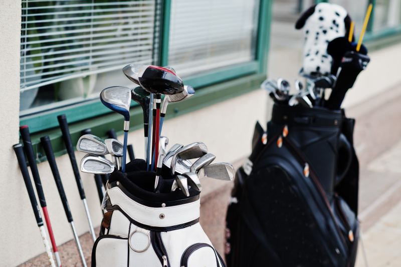 Many golf clubs in bag at pavement.