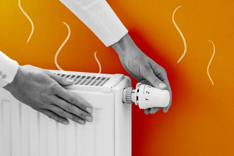 Close-up of a hand turning a home heater dial