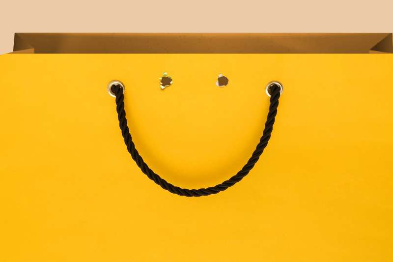 Photo-illustration of a shopping bag, with its handle forming a smile.