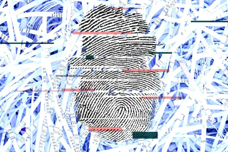 Black fragmented fingerprint on top of shredded paper