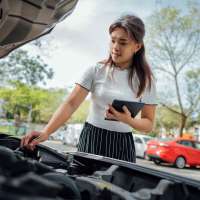Automobile insurance adjuster using digital tablet to inspecting damage to vehicle.