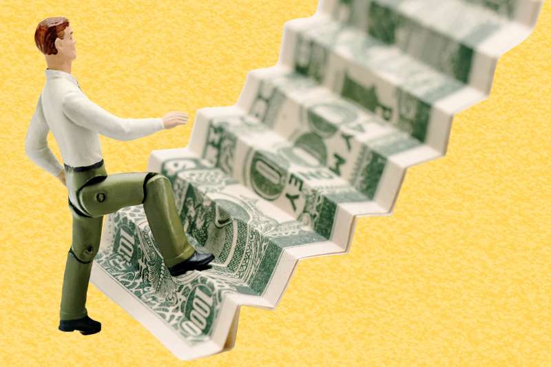 Photo-illustration of a figurine walking up a dollar bill folded into stairs.