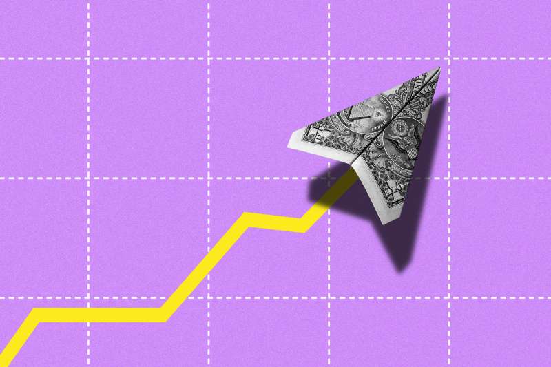 Photo illustration of a US dollar paper airplane flying upwards with a stock line trace behind it