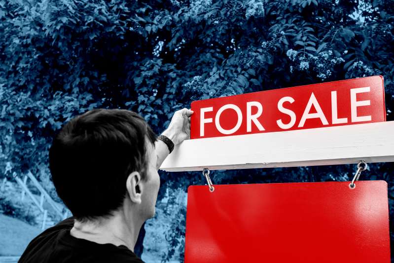 Close-up rear view of real estate agent adjusting for sign in front yard of house