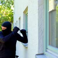 Burglar with crowbar breaking window