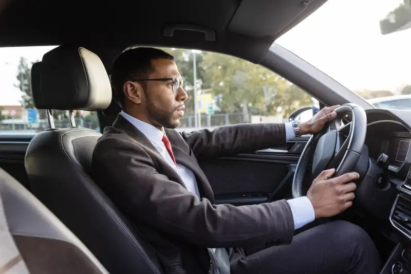 Man wearing a suit driving a car