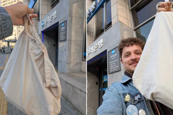 Photo of Adam Hardy holding a tote bag in-front of a bank in Korea