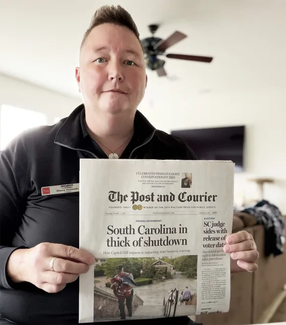 Photo of a person who is holding The Post And Courier newspaper.